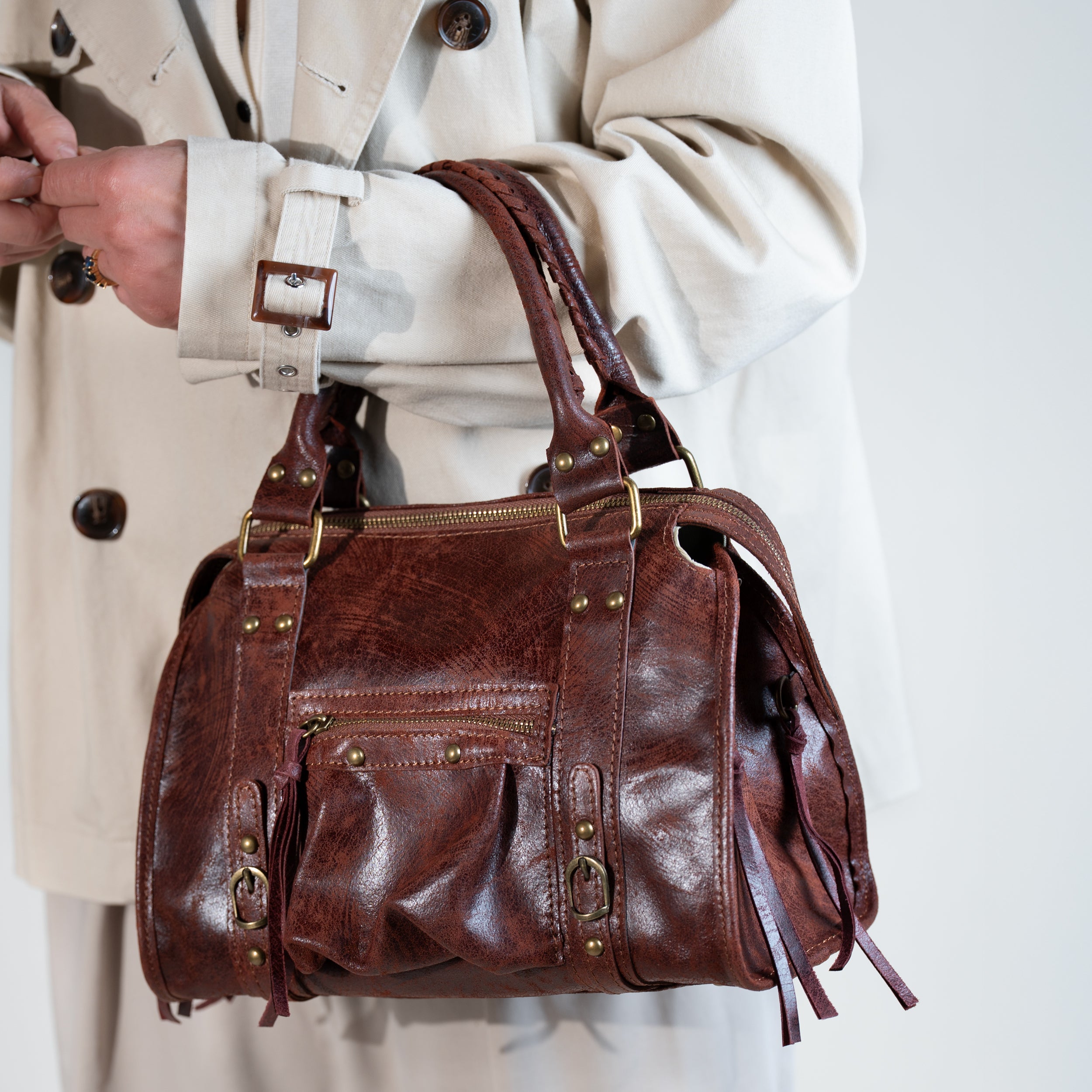 sac à main femme forme bowling porté creux de bras en cuir vieilli acajou vintage avec trench beige
