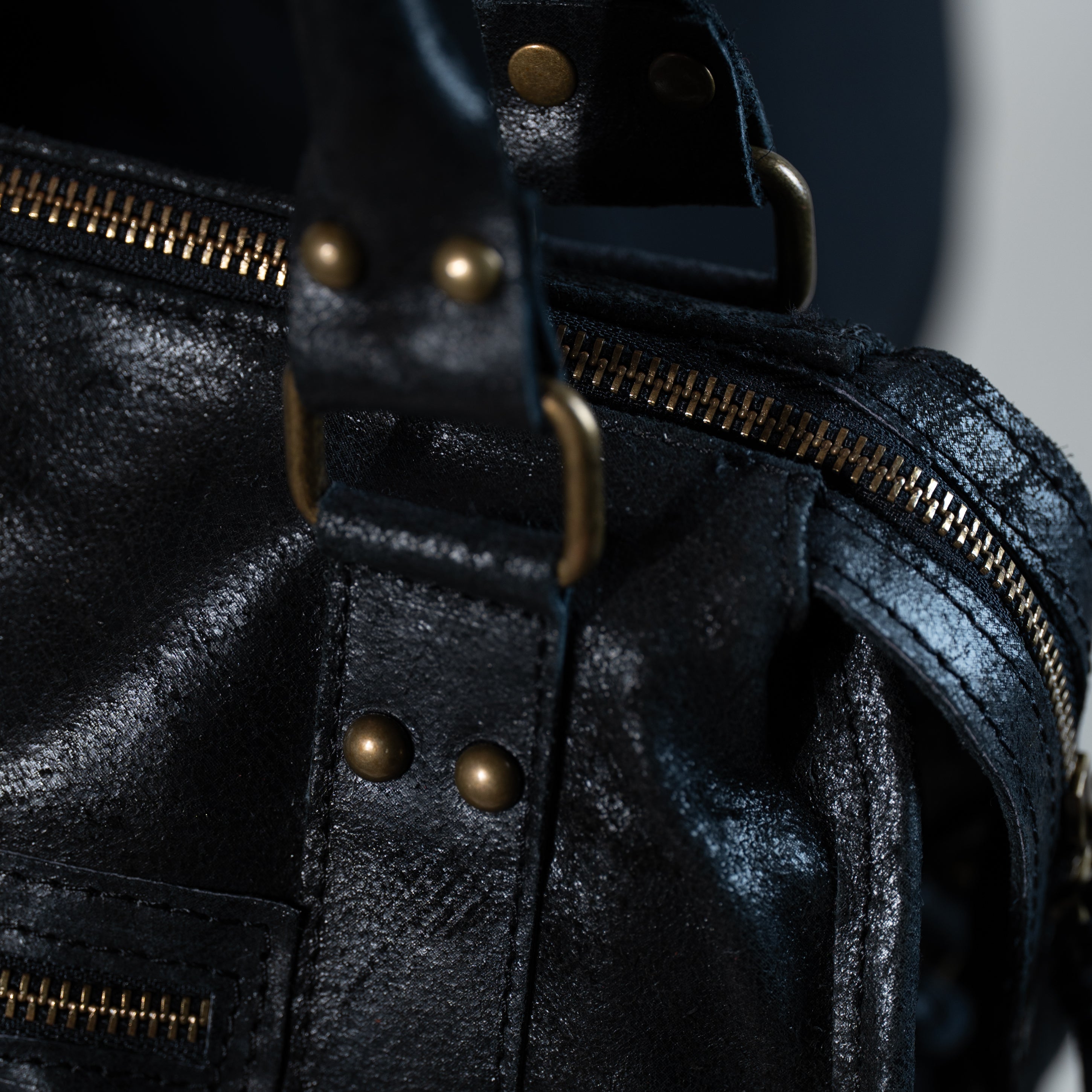 focus sur le cuir vieilli noir et la bijouterie dorée d'un main femme forme bowling vintage 