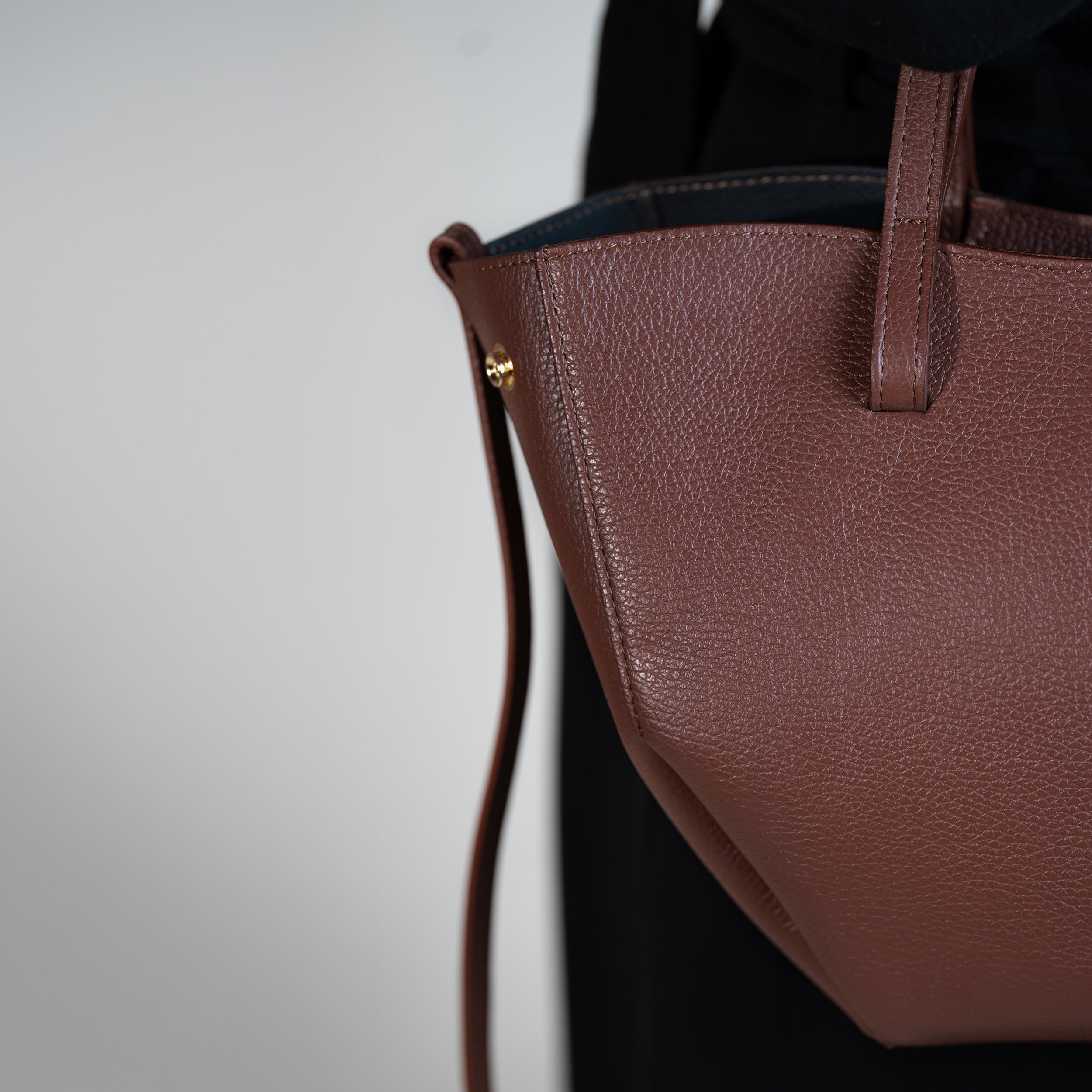 focus sur côté d'un sac cabas pour femme forme trapèze en cuir lisse brun