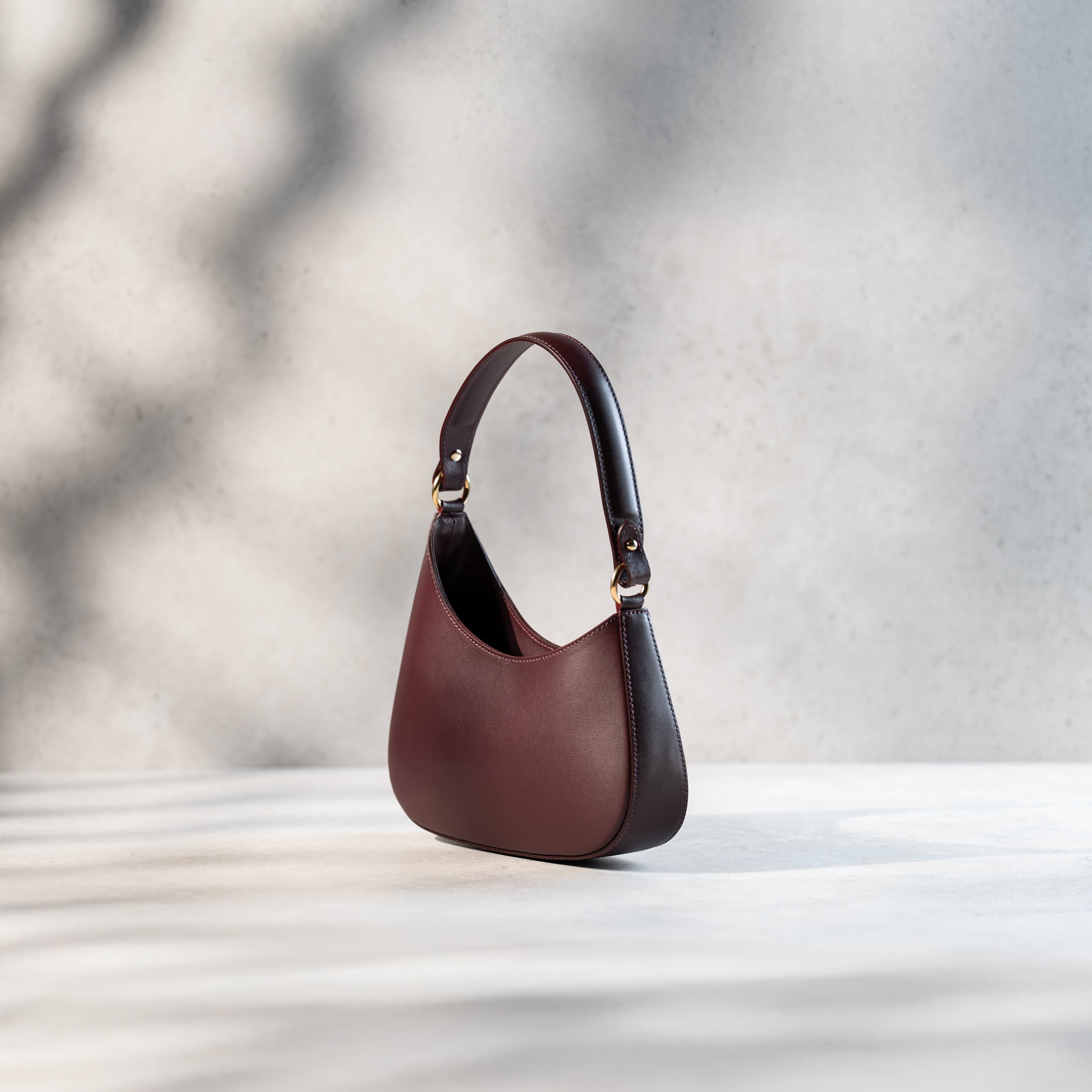 sac à main forme hobo demi lune asymétrique pour femme en cuir lisse bordeaux de côté