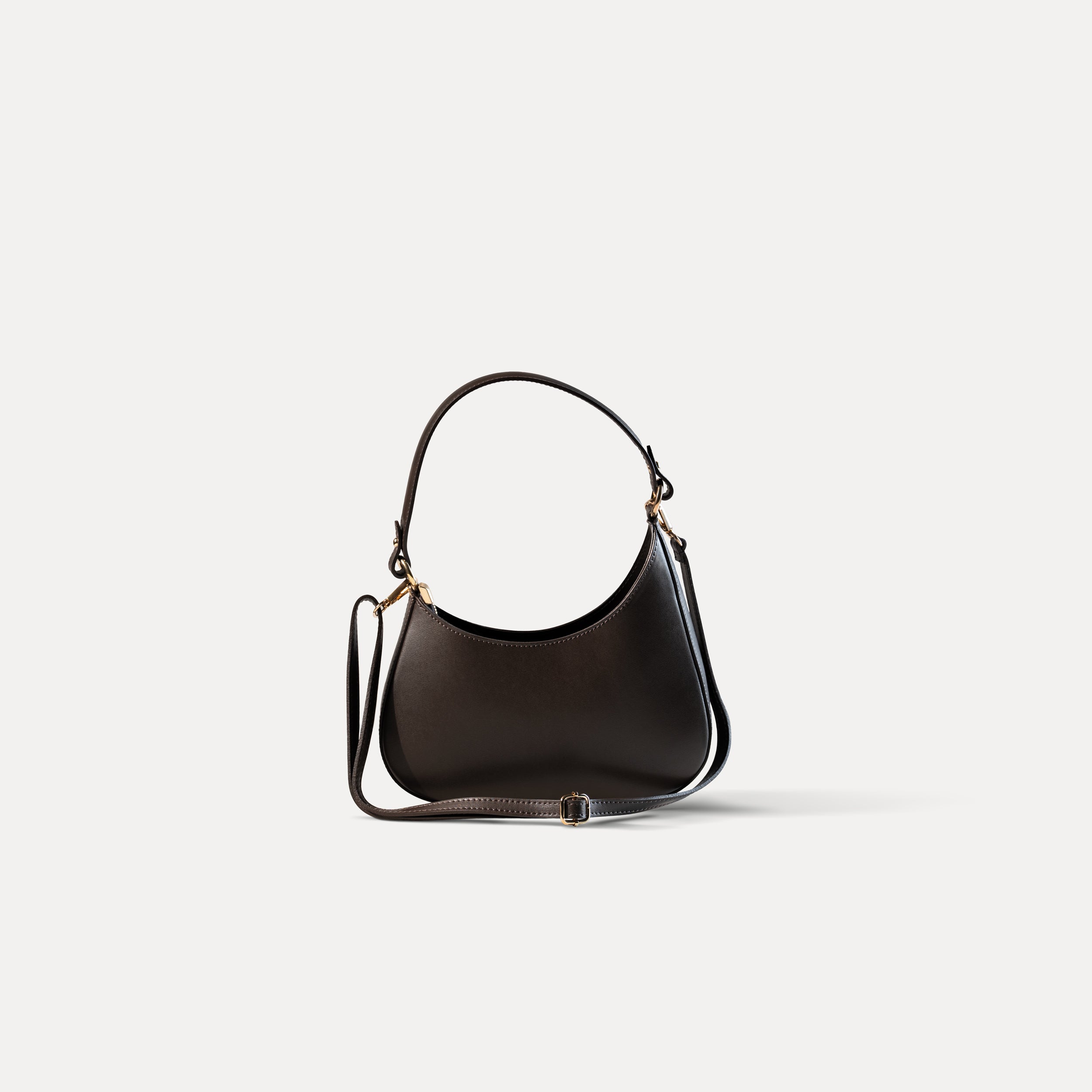 sac à main forme hobo demi lune asymétrique pour femme en cuir lisse marron de côté fond blanc