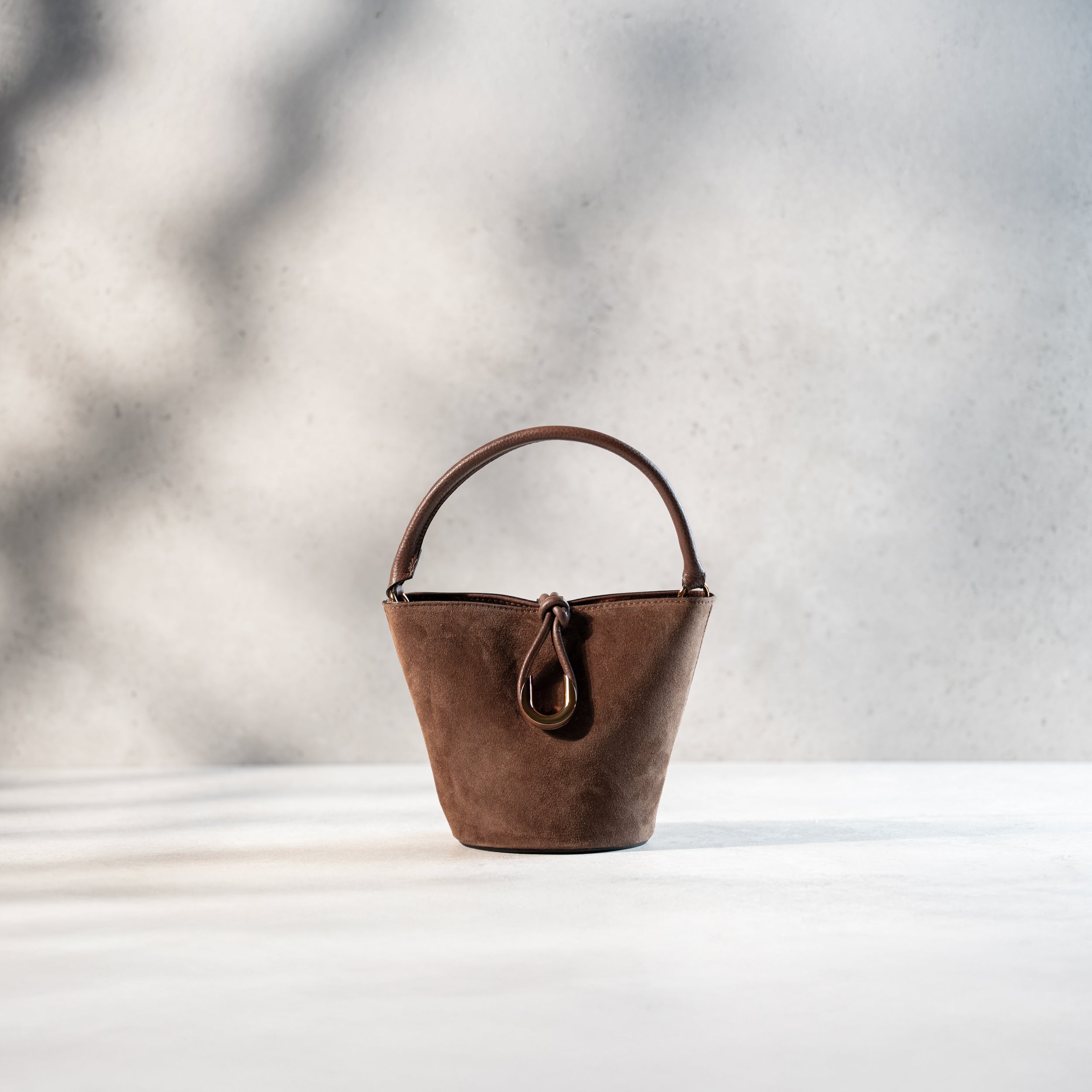 sac à main femme en cuir suédé ou daim brun en forme seau avec un fermoir doré original fermé