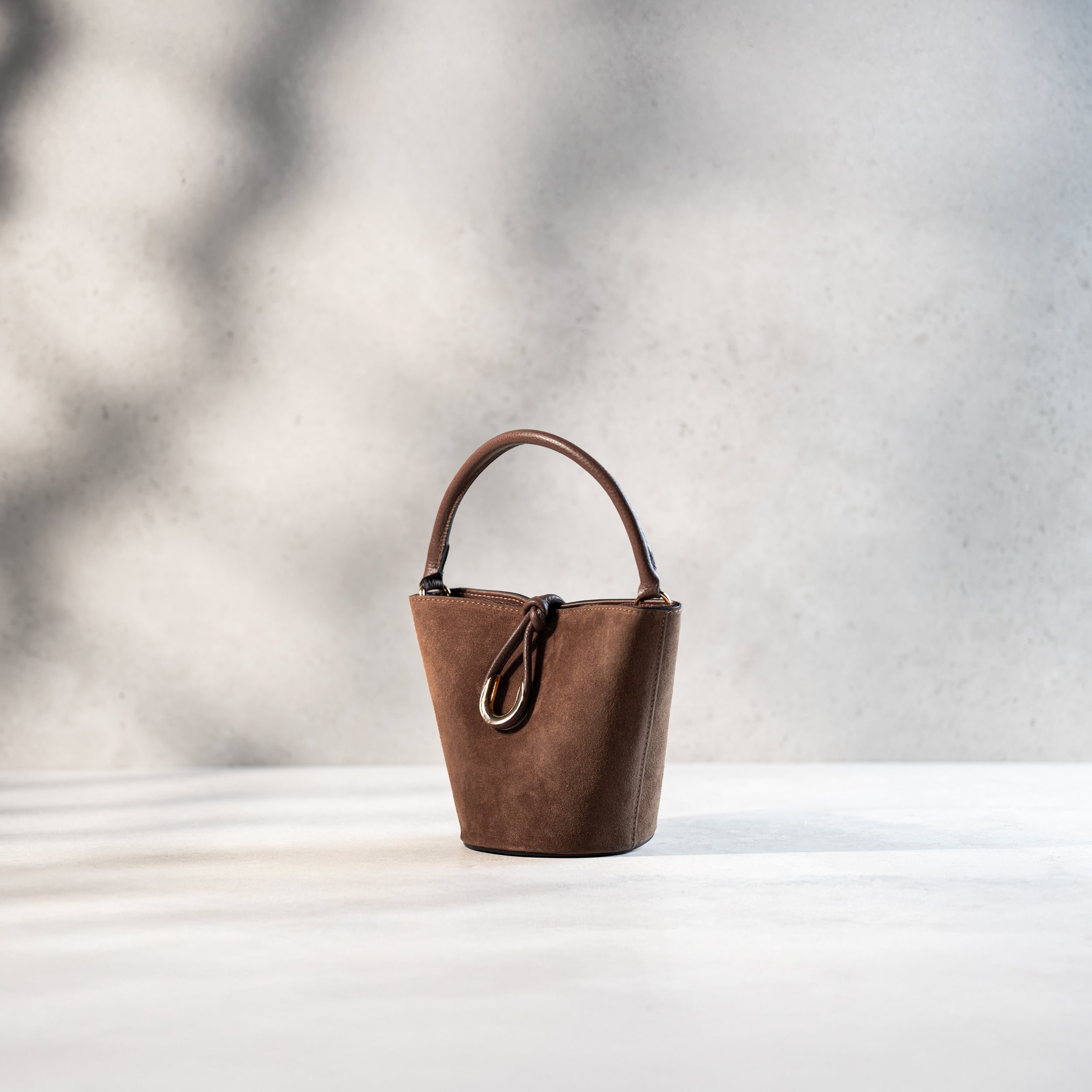 sac à main femme en cuir suédé ou daim brun en forme seau avec un fermoir doré original de côté