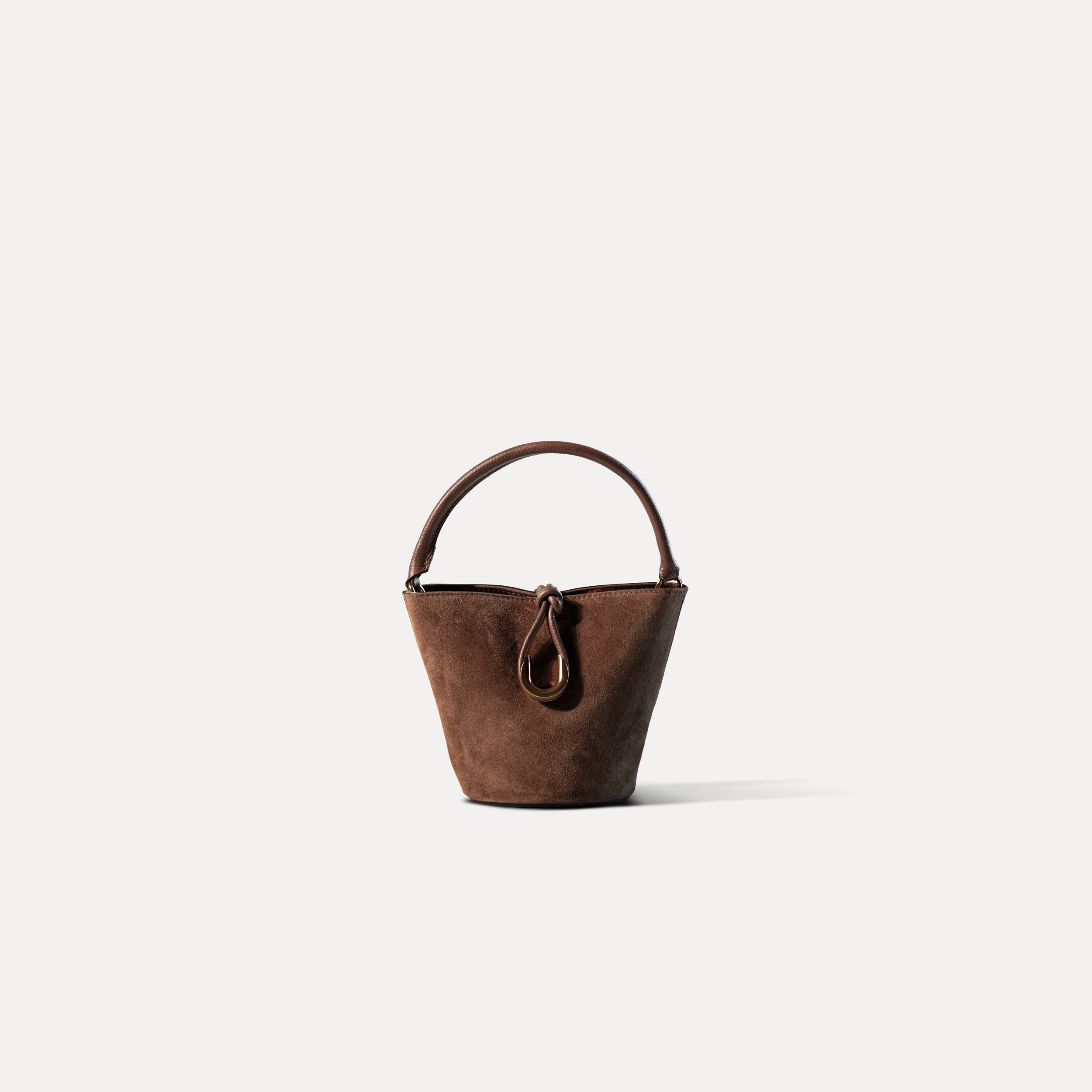 sac à main femme en cuir suédé ou daim brun en forme seau avec un fermoir doré original sur fond blanc