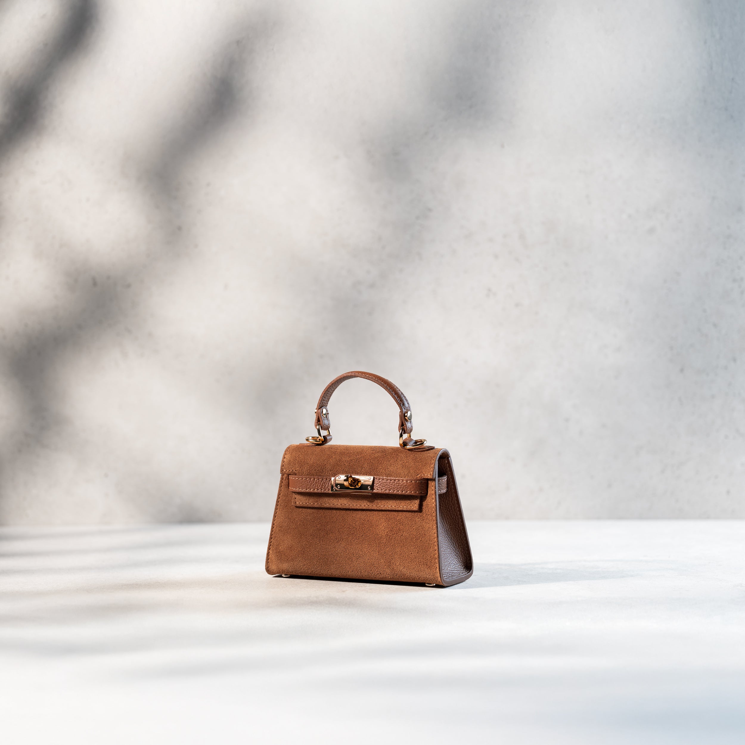 sac à main femme en daim top handle avec fermoir tourniquet fermé et bijouterie doré dans un cuir suédé camel de côté