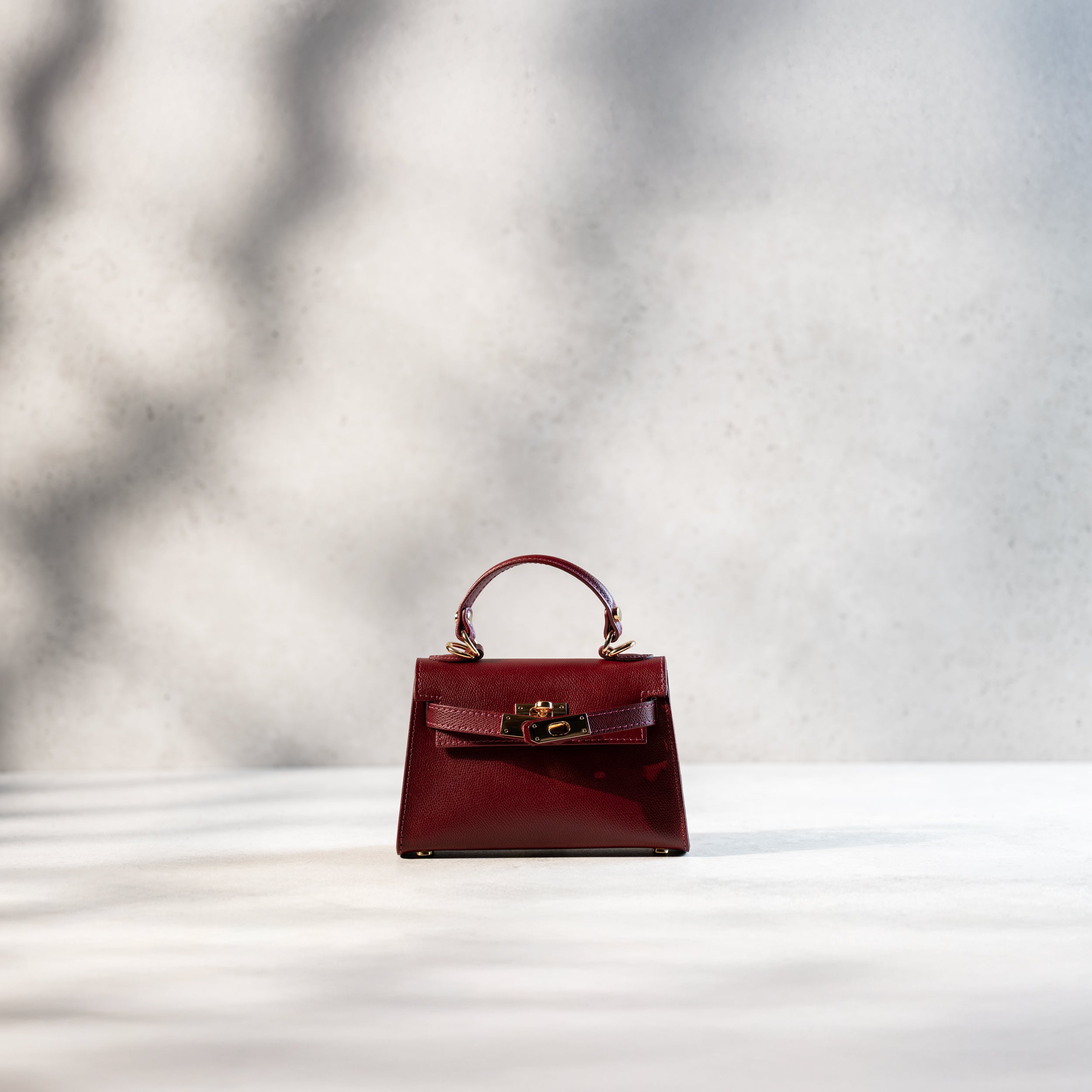 sac à main femme en cuir saffiano top handle avec fermoir tourniquet ouvert et bijouterie doré dans un cuir de qualité bordeaux et clous de fond de sac 